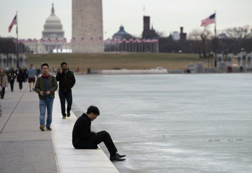 سائح يجلس على ضفة بحيرة لينكولن المتجمدة في واشنطن