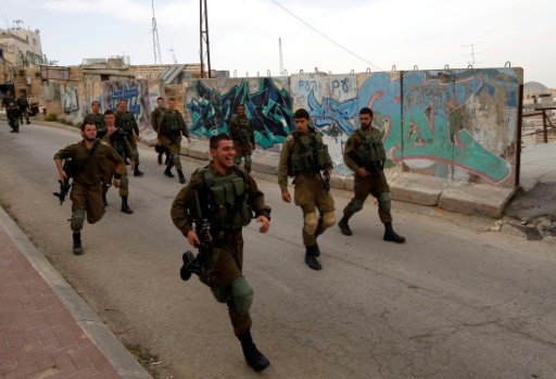 جنود إسرائيليون يجرون في شارع الشهداء في الخليل في