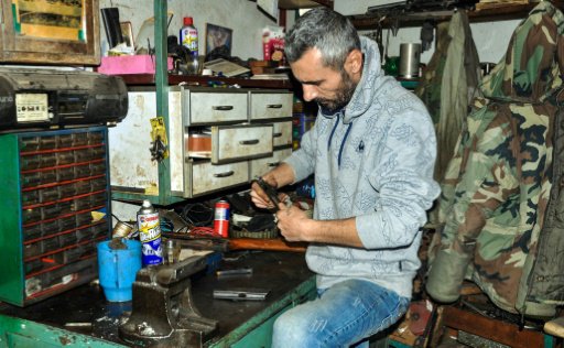 السوري عبود جان يعمل على صيانة مسدس في متجره في ال