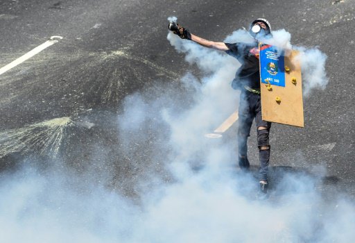 متظاهر من المعارضة الفنزويلية يعيد رمي عبوة مسيلة 