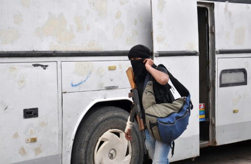 مسلح سوري معارض يستعد لركوب حافلة لمغادرة حي الوعر