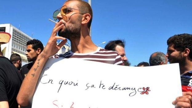 متظاهر تونسي يحمل لافتة كتب عليها ما الذي يضايكم ف