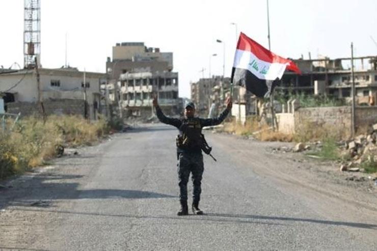 عنصر من الشرطة الاتحادية العراقية يرفع علم العراق 