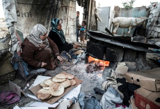 امرأة فلسطينية تعد الخبز قرب منزلهم في مخيم خان يو