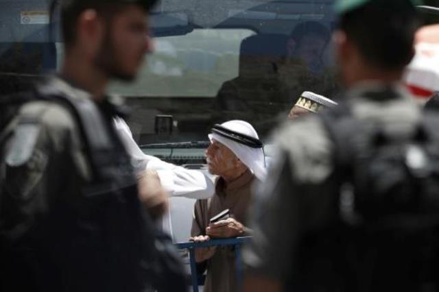 شرطي من خفر الحدود الاسرائليلي يدقق في هوية فلسطين