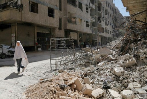 فتاة تسير بالقرب من مبنى دمره القصف في بلدة عين تر