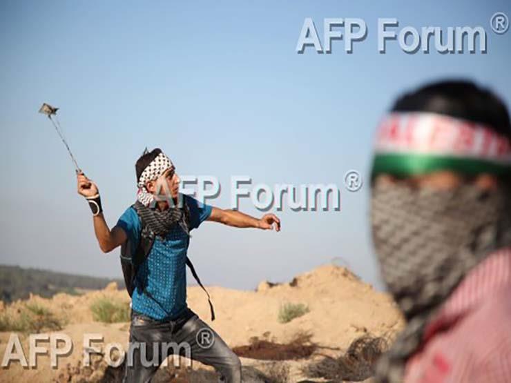 شاب فلسطيني يلقي الحجارة باتجاه جنود إسرائيليين في