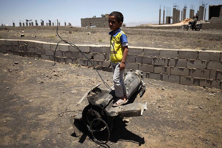 طفل يقف على جزء من قذيفة مدفعية سقطت بالقرب من منز