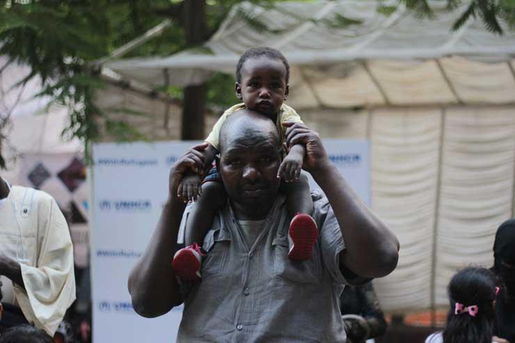 أحد المشاركين في اليوم العالمي للاجئين بصحبة طفله