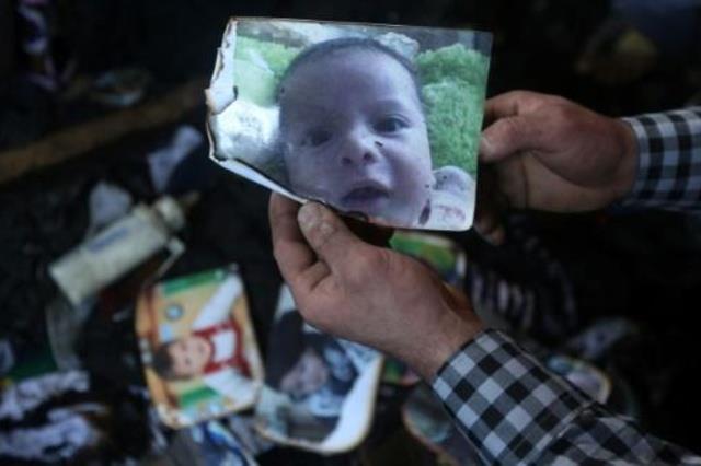 رجل يحمل صورة الطفل علي دوابشة الذي قضى في الهجوم 