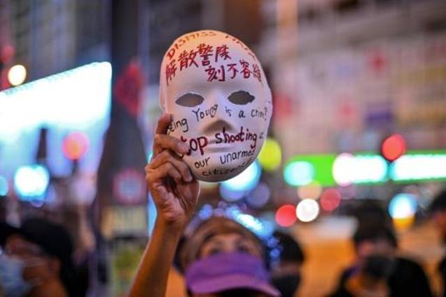 سيدة ترفع قناعا خلال تظاهرة في هونغ كونغ