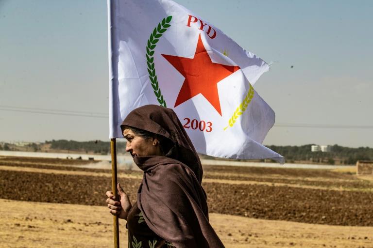 امرأة كردية في سوريا تلوح بعلم حزب الاتحاد الديموق