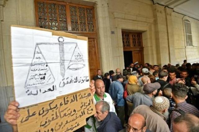 جزائريون يرفعون لافتة للمطالية بتحقيق العدالة أمام