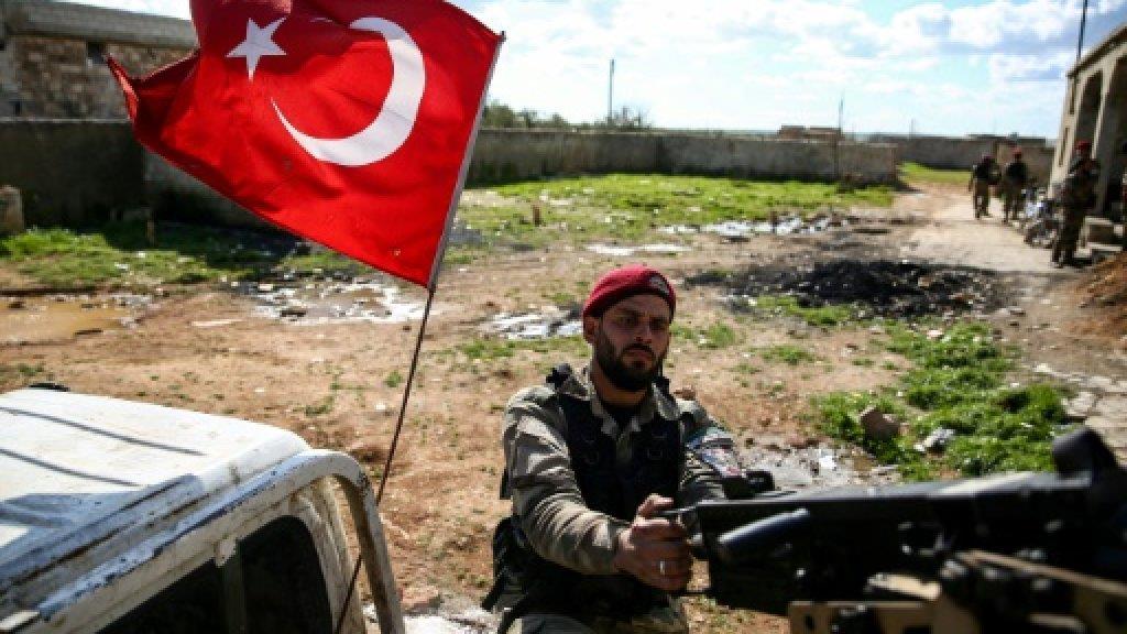 علم تركيا يرفرف على مركبة تقل مقاتلا سوريا في قوة 