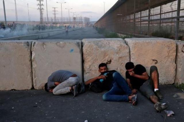 متظاهرون فلسطينيون يحاولون الاحتماء خلف جدار خلال 