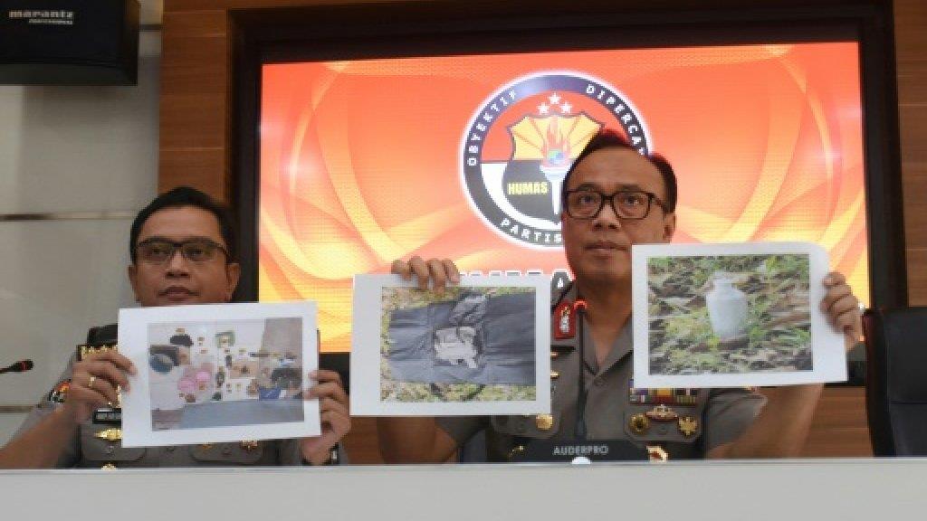اثنان من ضباط الشرطة الإندونيسية يعرضان صور مشتبه 