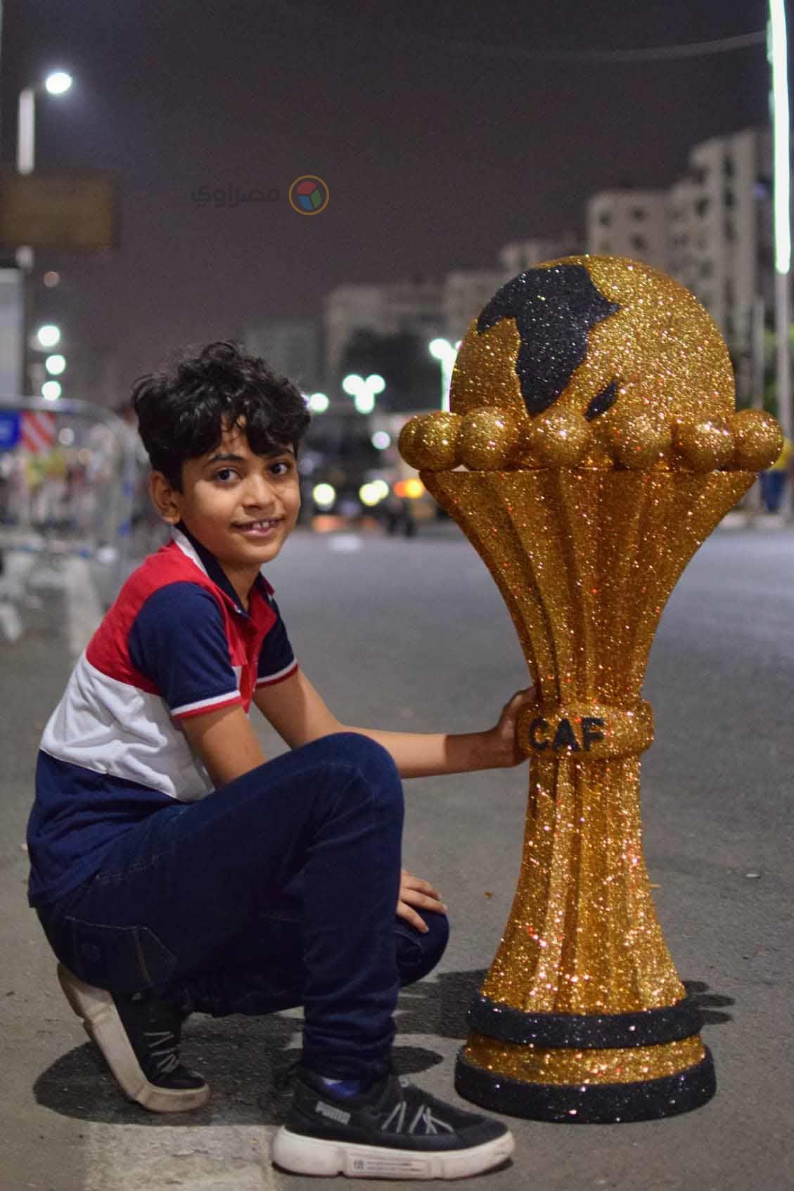 الطفل سيف بجانب مجسم لكأس الأمم الأفريقية