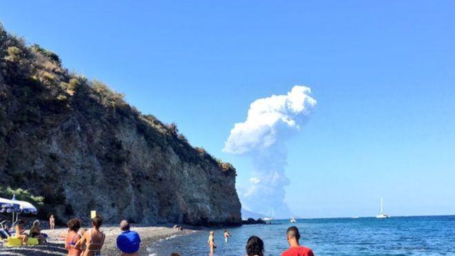 سياح يشاهدون تصاعد الدخان من البركان من على جزيرة 
