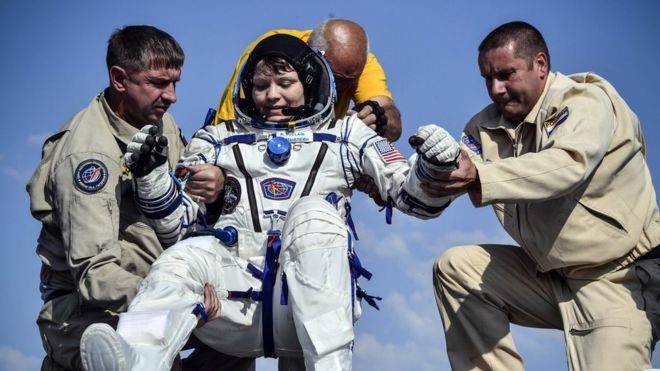 أشخاص يساعدون رائدة الفضاء، آن مكلين، لدى عودتها م