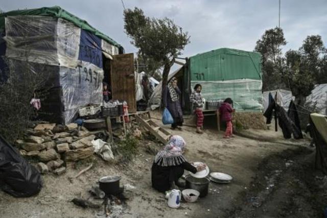 امرأة تغسل اطباقاً في مخيم مؤقت قرب مخيم موريا للا