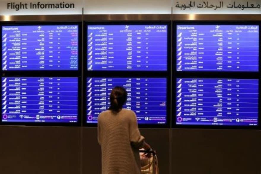 مسافرة تنظر إلى لوحة الرحلات المغادرة في مطار الدو