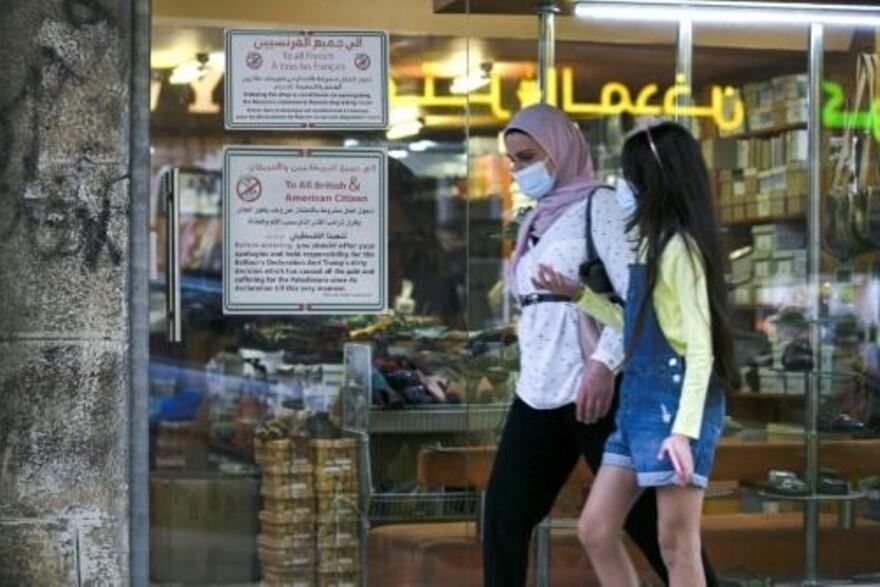 شابتان أمام متجر أحذية وضع لافتتين تطالبان المواطن