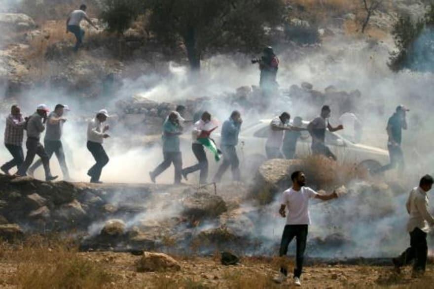  متظاهرون فلسطينيون يركضون وسط دخان الغاز المسيل ل