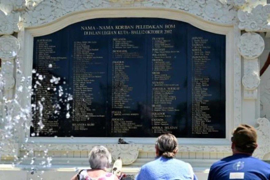 سياح أجانب أمام نصب تذكاري كُتبت عليه أسماء ضحايا 