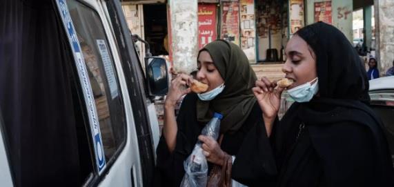 شابتان سودانيتان تتناولان خبزا تقليديا في الخرطوم