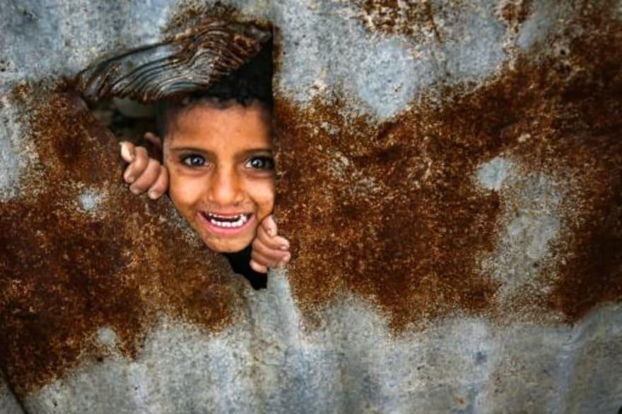 طفل فلسطيني ينظر من فتحة في لوح زينك مستخدم كجدار 