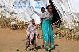  لاجئة إثيوبية مع طفليها في مخيم أم راكوبة في السو