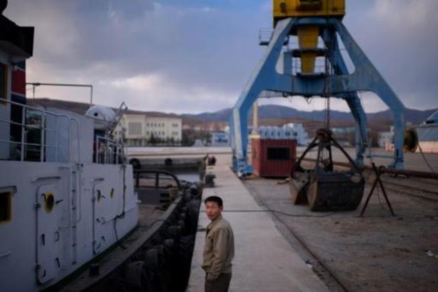 عامل يقف قرب سفينة في ميناء راجين قرب مدينة راسون 