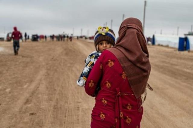 سورية تحمل طفلا في مخيم واشوكاني للنازحين قرب الحس