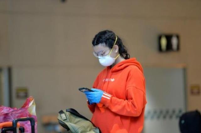 امرأة ترتدي قناعا واقيا وقفازات في مطار لوغان