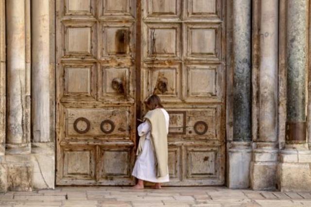 مصل يقف أمام أبواب كنيسة القيامة في البلدة القديمة