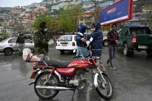 شرطي أفغاني يفتش راكب دراجة نارية في نقطة تفتيش