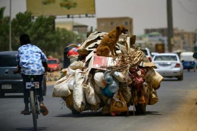 فتى سوداني يعبر على دراجته قرب مركبة تنقل القمامة 