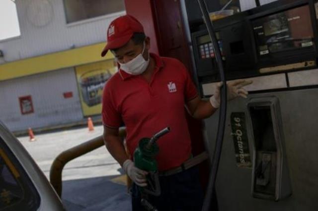 عامل في محطة وقود يضع قناعا وقفازات في كراكاس