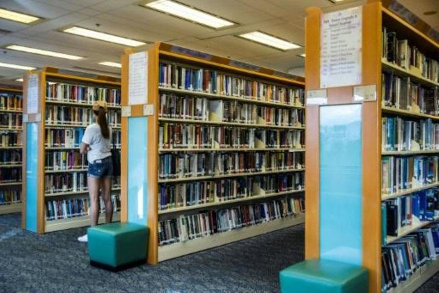 امرأة تفحص كتبا في مكتبة عامة في هونغ كونغ