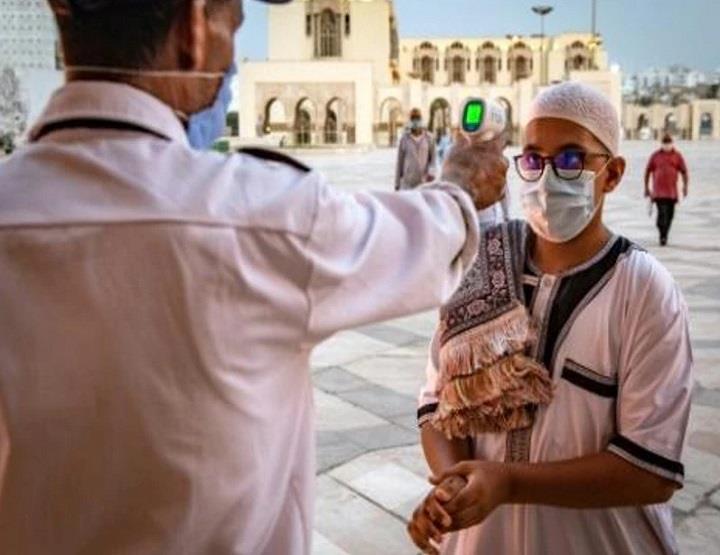   عامل يقيس درجة حرارة جسم المصلين المسلمين الوافد