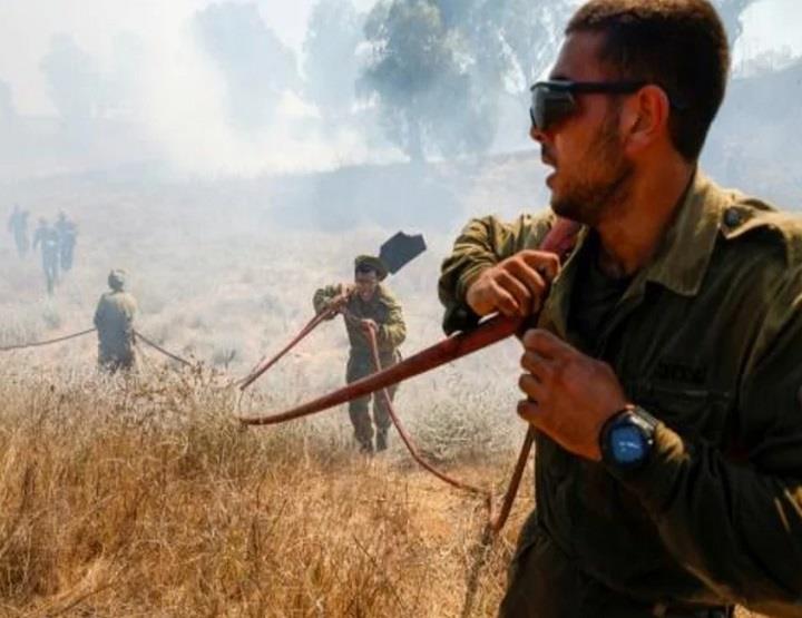 عسكريون إسرائيليون بحاولون إطفاء حريق اندلع في حقل