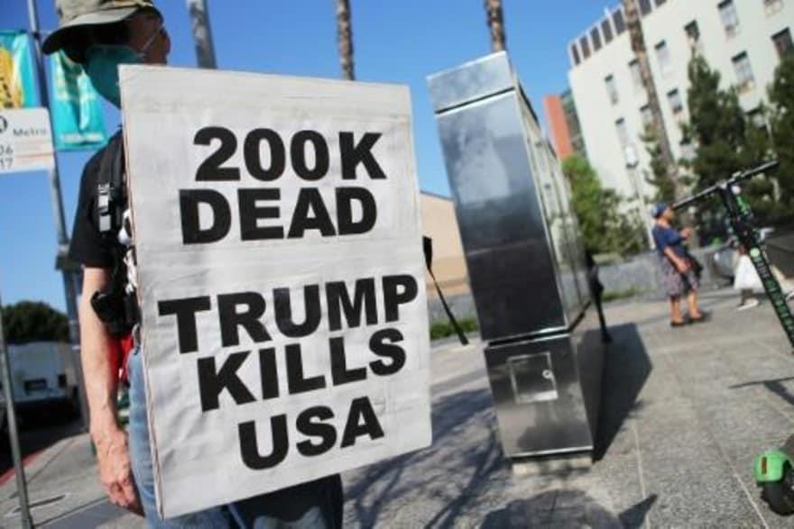  يرفع لافتة كتب عليها "مئتا ألف وفاة، ترامب يقتل ا