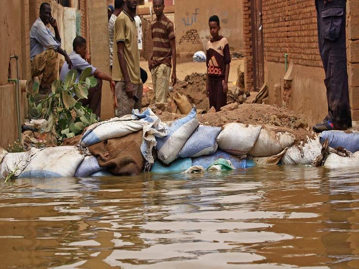 سودانيون يقفون وسط مياه فاضت من نهر النيل في جزيرة