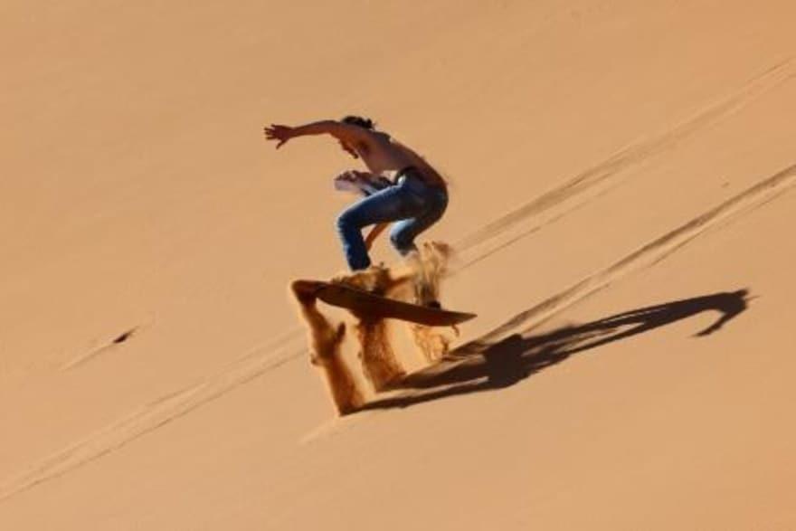 سائح يمارس رياضة التزلج على الرمال في دبي