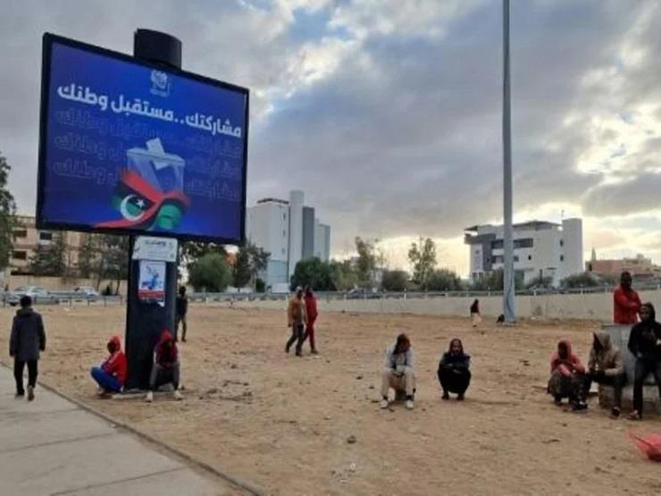  ليبيون قرب لوحة انتخابية في طرابلس في 14 كانون ال