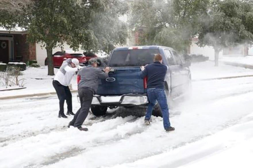 سكان يساعدون سائقا علقت سايرته في الثلج في تكساس