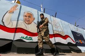  عنصر من القوات العراقية يمر أمام جدارية عليها صور
