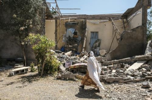  امرأة تمر من أمام منزل دمره قصف القوات الفدرالية 