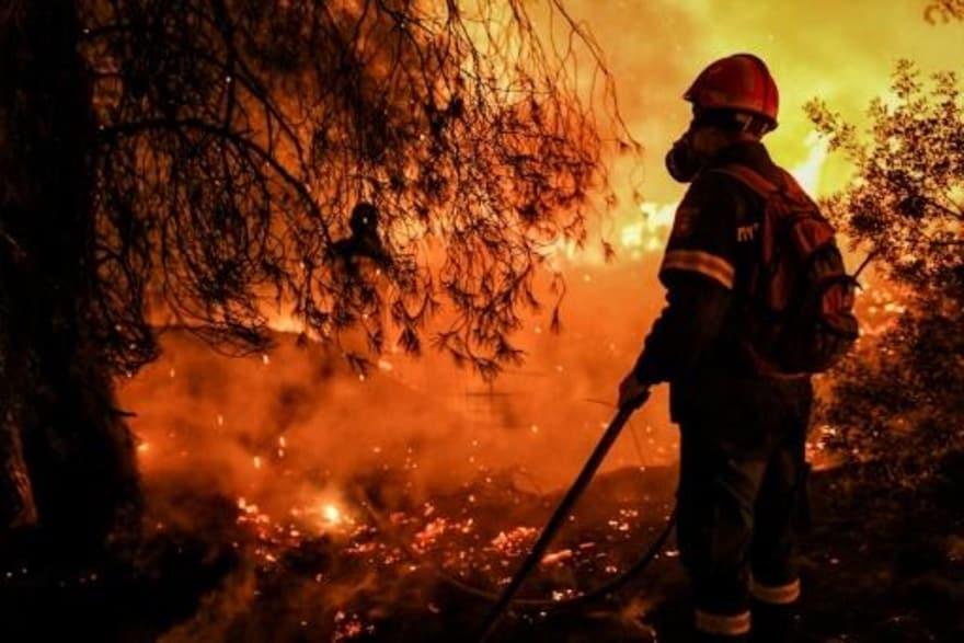 رجل إطفاء يكافح حريق غابات في سخينوس اليونانية