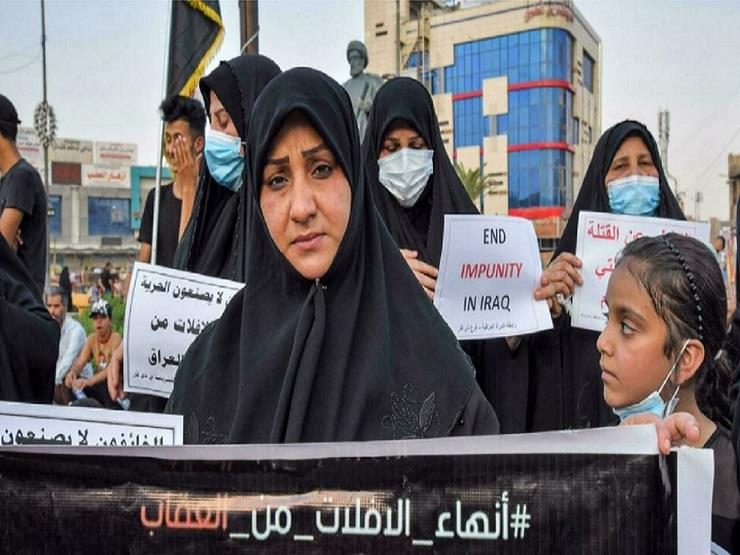 نساء يحملن لافتات كتب عليها شعار "إنهاء الإفلات من